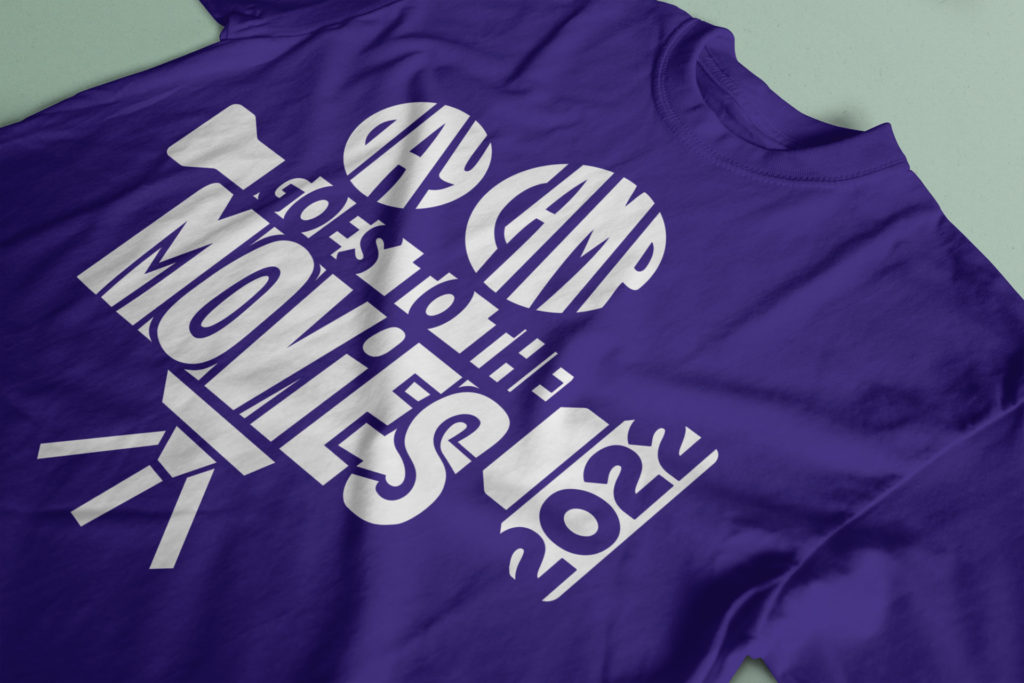 a purple tshirt with a white logo screen printed on it, reading 'Day Camp Goes to the Movies 2022'
