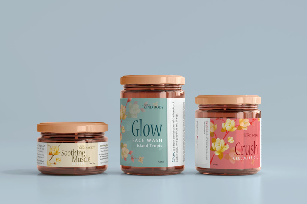Three amber jars sit on a pale blue background. The middle jar is tallest and wrapped with an aqua and sand colored floral product label. The right jar is a bit shorter and wrapped with a salmon pink and yellow floral product label. The left jar is shortest of the three and wrapped in a narrow pale yellow and brown floral product label.